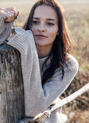 Beautiful brunette woman in sweater in rural area
