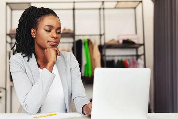 Concentrated Woman Sitting at Desk Looking at Laptop