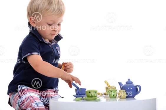 little boy playing with a doll's tea set