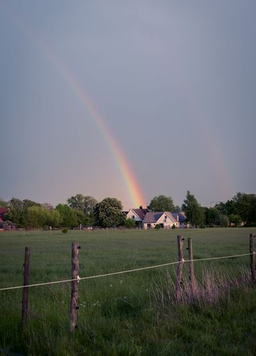 Rainbow ending at rural house in the countryside in...