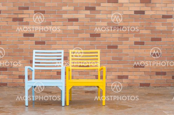 blue and yellow wooden chair and red brick wall