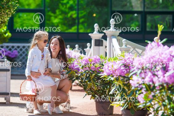 Adorable little girl and young mom enjoying warm day in tulip garden