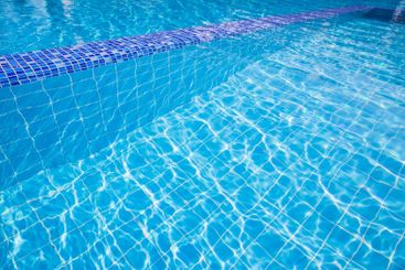 Clear water reflects sunlight in a serene swimming pool...