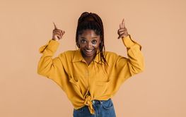 Young black woman with afro pigtails smiling and pointing...