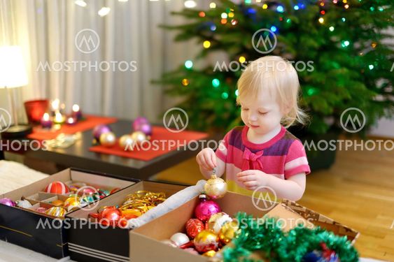 Adorable little girl decorating a Christmas tree