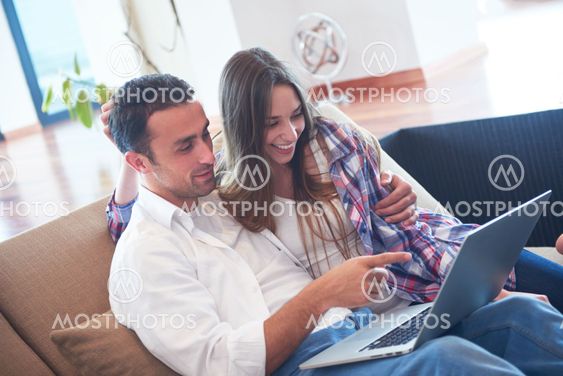 relaxed young couple working on laptop computer at home