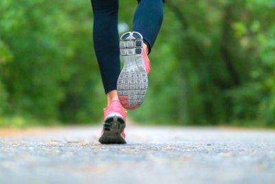 Running woman in the forest. Close-up of sneakers.