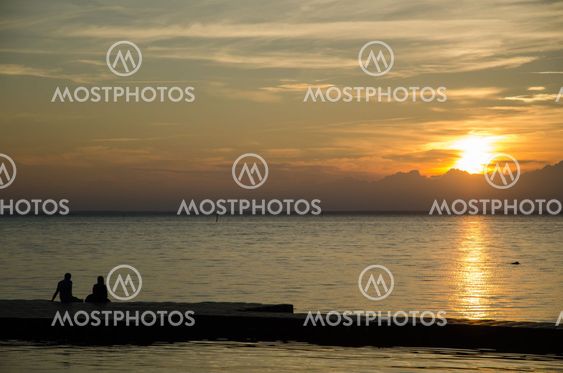 Couple watching sunset at a pier