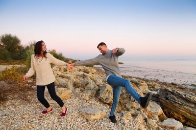 Young couple at rocky seacoast in sunset