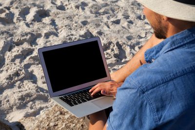 Man using laptop on the beach