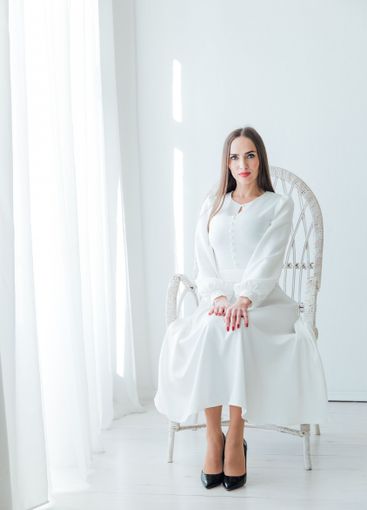 Beautiful woman in white summer dress sitting in...