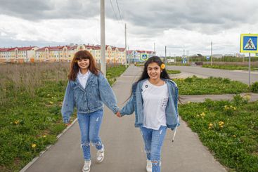 Two smiling girls in denim suits on a walk. Positive...