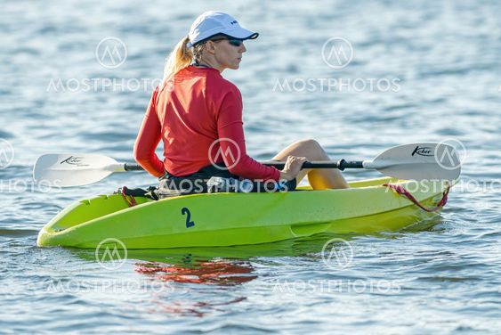 Female canoeist in th rescue team in red shirt in a green...