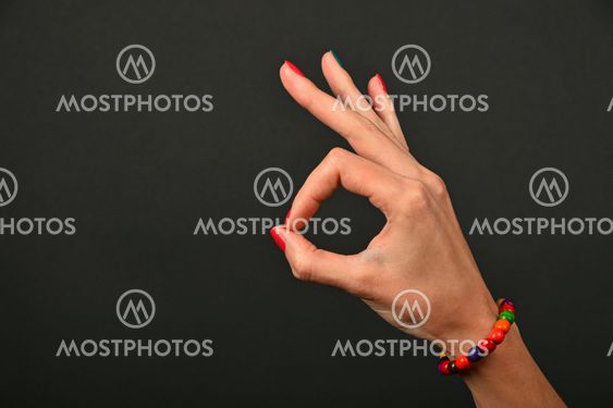 Woman hand with beads shows ok gesture over black
