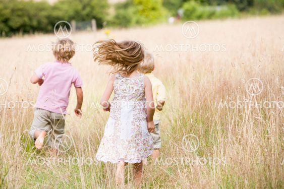 Three young children running outdoors