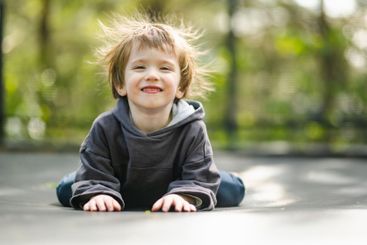 Little boy jumping on a trampoline in a backyard on warm...