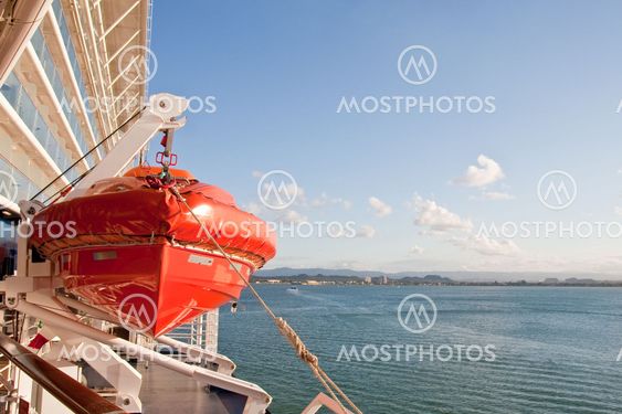 Orange Lifeboat Hanging from Ship Over Blue Sea