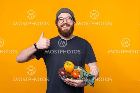Photo of young farmer showing thumb up and holding fresh...