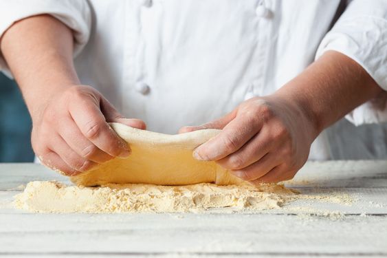 Closeup hand of chef baker in white uniform making pizza...