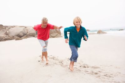 Grandfather Chasing Grandson Along Winter Beach
