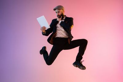 Full length portrait of happy jumping man in neon light...