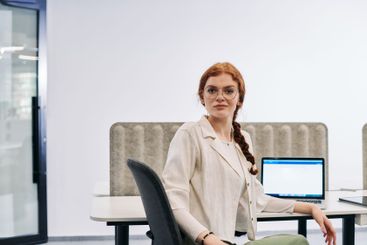 A modern businesswoman with striking orange hair sitting...