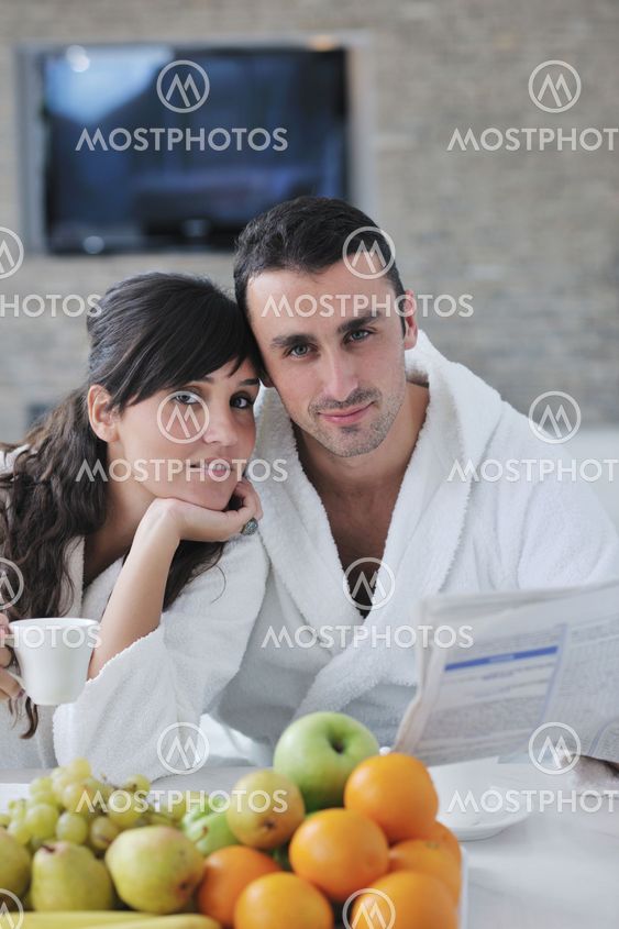 Happy couple reading the newspaper in the kitchen at breakfast