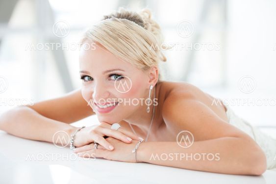 Smiling beautiful blond bride sitting at a table