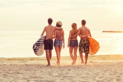 smiling friends in sunglasses with surfs on beach