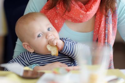 Baby boy having piece of bread