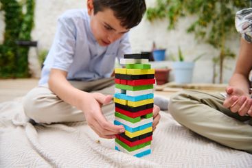 Boy concentrating on stacking colorful blocks outdoors...
