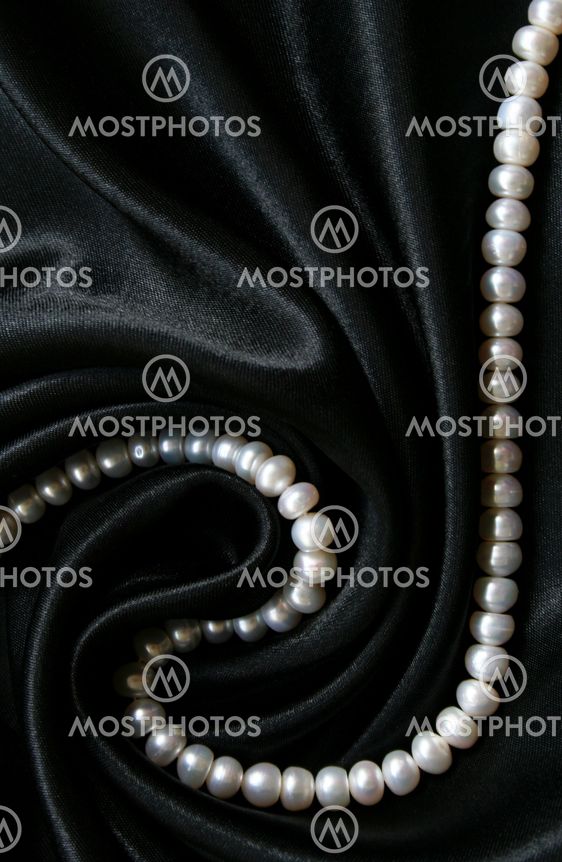 White pearls on the black silk as background