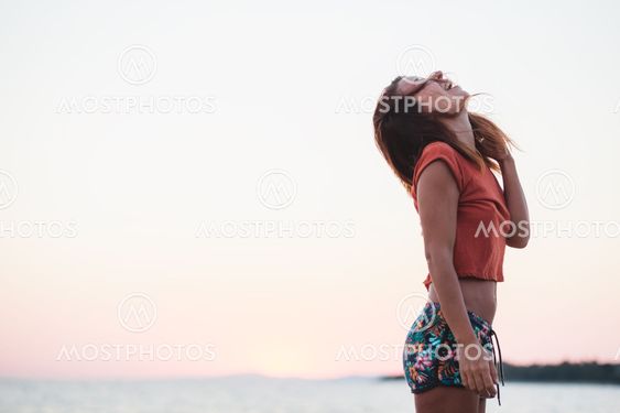 Young woman enjoying sunset by the sea