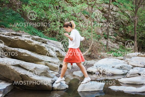 Young woman jumping over the creek