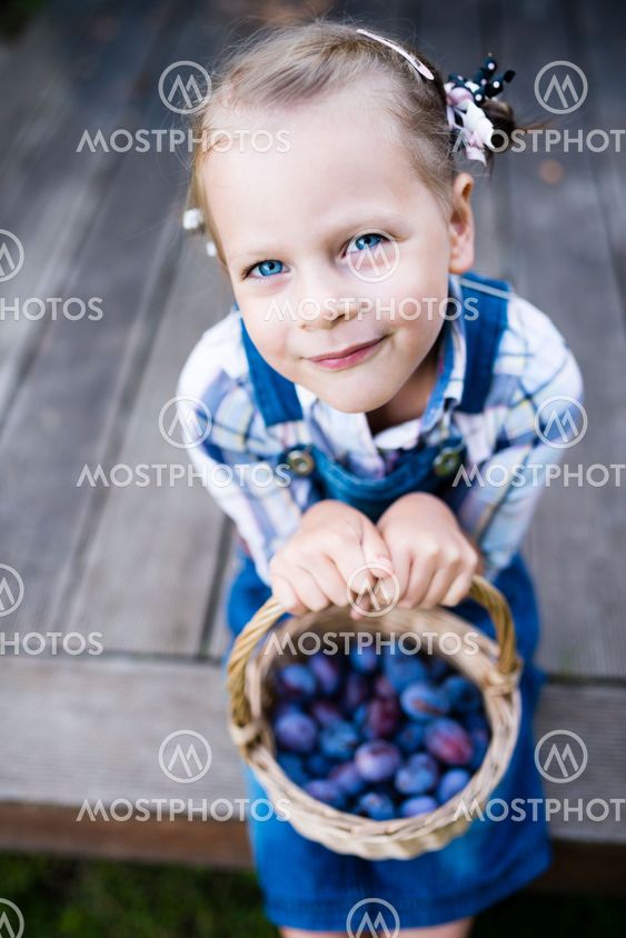 Funny little child girl with basket full of plums