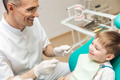 Smiling dentist doing dental treatment to little boy