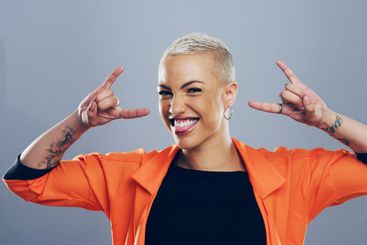 Portrait, edgy or happy woman with rock hand gesture in...