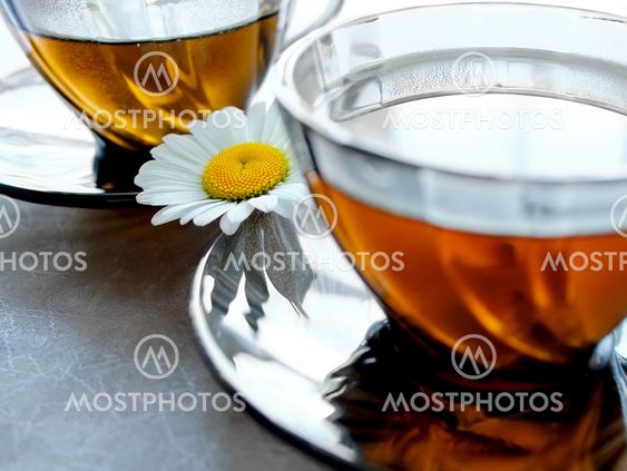 Closeup cups of tea with a camomile between two saucers