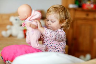 Adorable cute little toddler girl playing with doll....