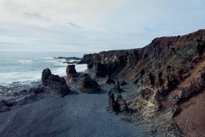 aerial view of rocky seashore with grey sand,...
