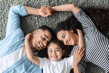 Portrait of happy middle eastern family cuddling on floor