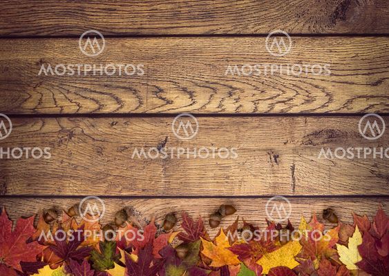 Autumn leaves and acorns on rustic wooden background
