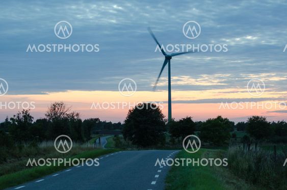 Wind turbine by a winding road at late evening