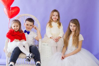 four children with red balloons on a purple holiday...