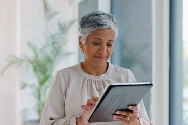 Business woman, tablet and typing in hallway at modern...