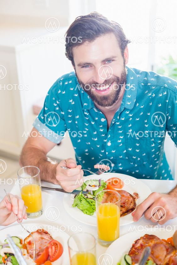 Young man sitting at dining table smiling