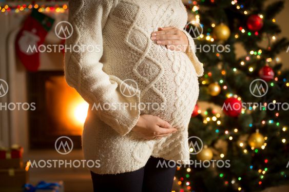 pregnant woman posing against fireplace and Christmas tree