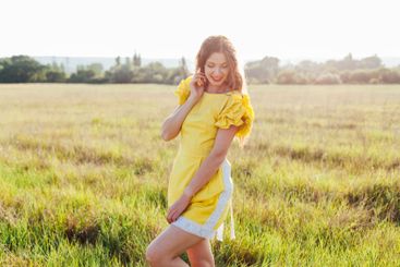 Beautiful young woman in summer yellow dress walking in...
