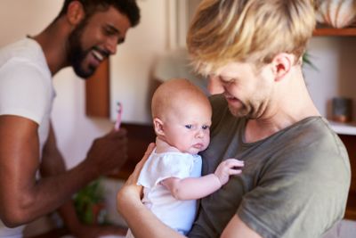 Loving Male Same Sex Couple Cuddling Baby Daughter In...