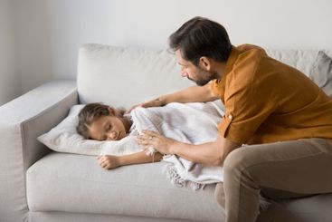 Dad covering with warm plaid his little sleeping daughter